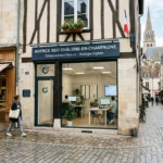 Agence seo Châlons-en-Champagne: façade d'une agence au signage bleu, clients et cyclists dans une rue pavée centrée sur le référencement naturel et stratégie digitale.